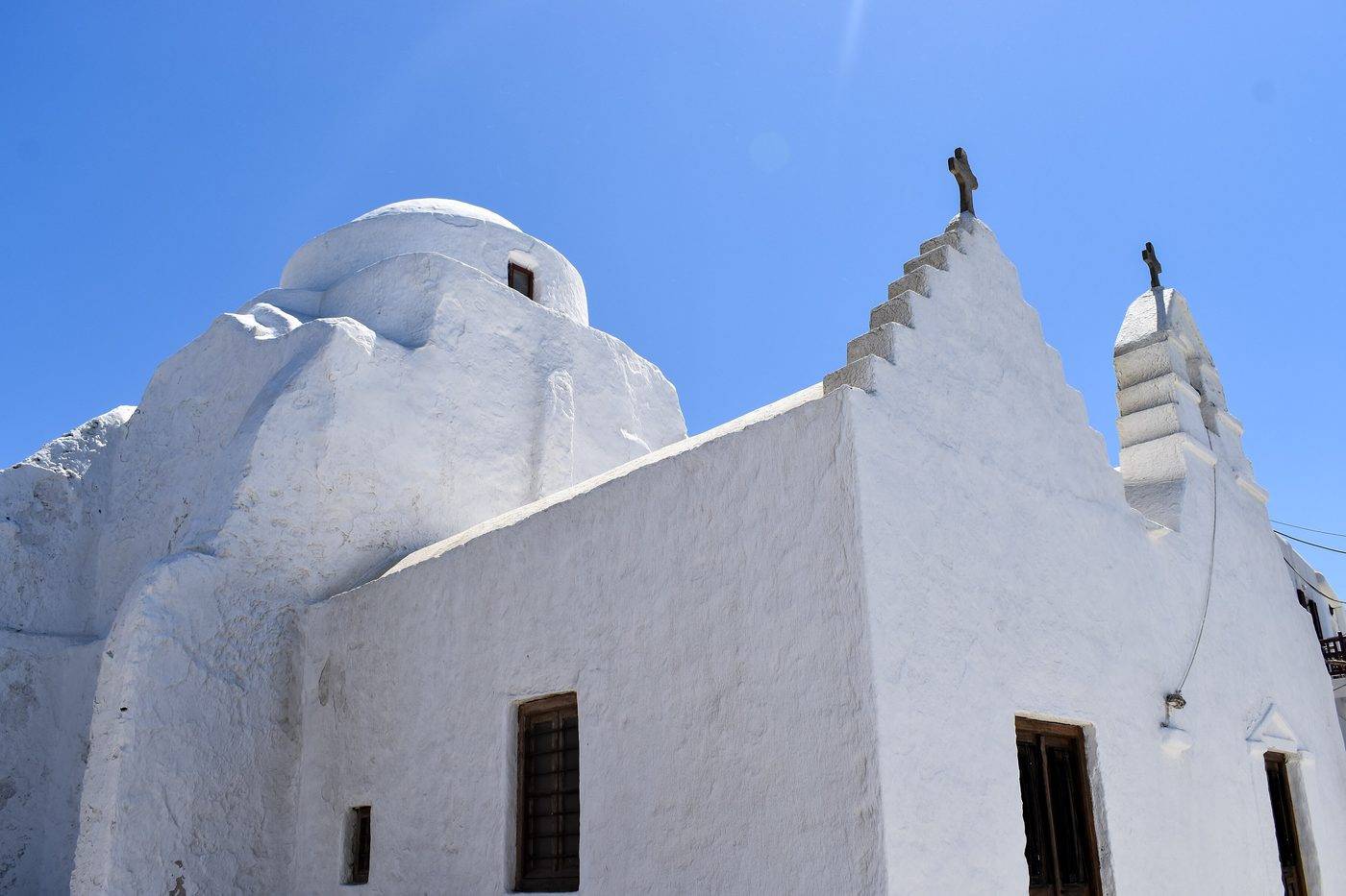 The whitewashed church of Panagia Paraportiani in Mykonos Town against a deep blue sky